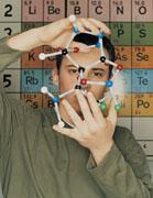 A students in front of a periodic table with scientific apparatus