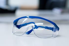Safety glasses, with blue edging, folded, sitting on a white blurred background