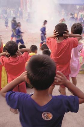 Children cover their ears as firecrackers go off at a bangkok temple