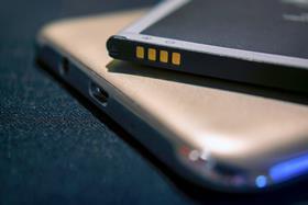 A close-up photograph of a mobile phone and a lithium ion battery