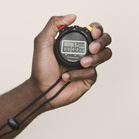 A photograph showing a hand holding a stopwatch