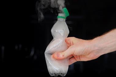 A hand squeezing a plastic bottle with vapour emerging from the neck