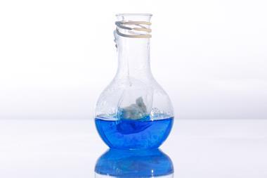 A round glass flask holding blue liquid and a teabag