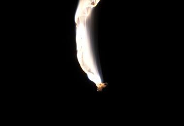 A photograph showing magnesium ribbon burning with a bright white flame against a black background