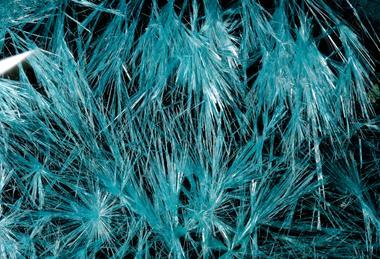 A photograph showing blue copper chloride crystals against a black background