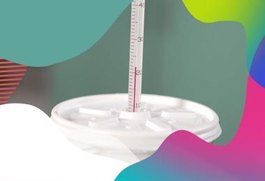 Thermometer stuck through hole in lid of polystyrene cup