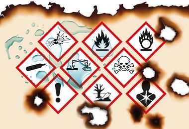 A piece of paper with warning symbols on that has been burned and splashed