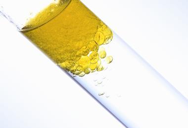 A yellow oil sits on top of a clear liquid in a test tube