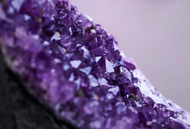 A close-up photograph showing a purple amethyst crystal