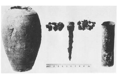 An old black and white photo of a cracked clay jar and some metal components