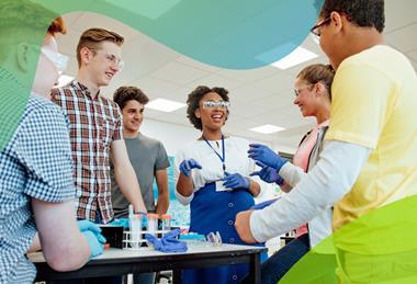 A teacher discusses an experiment with a group of students in a school laboratory, while wearing safety glasses and gloves