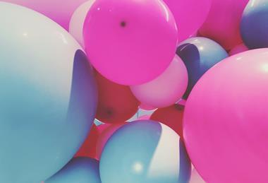 A photograph of balloons of different sizes and in different colours, including pink, blue and red