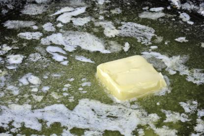 A close-up photograph of margarine melting in a pan