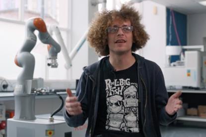 Photo of robot scientist creator, Benjamin Burger with robot in the background