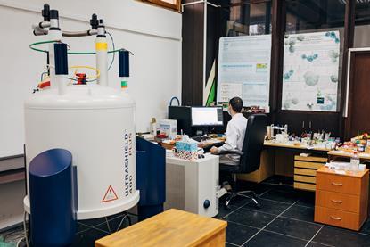 A scientist in a lab working on a computer and NMR machine
