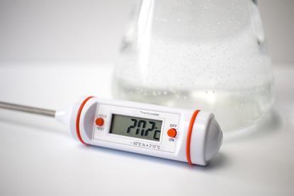 Digital thermometer in front of a conical flask.