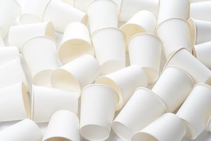 Plain white paper cups scattered across a white surface
