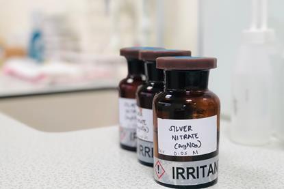 Three brown glass vials labelled as containing silver nitrate on a white-grey laboratory bench