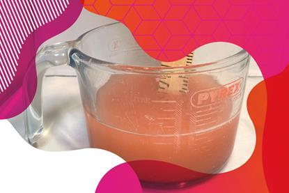 Photo of orange fizzy drink in a glass jug with a wooden ruler 
