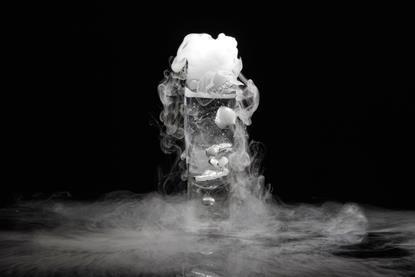 Dry ice in a glass producing a white-grey 'fog' against a black background