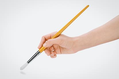 A hand holding a brush ready to make a white surface