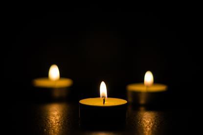 Three small candles or tea lights burning against a black background