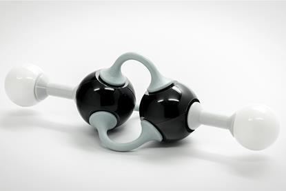 A plastic model of a molecule of ethyne, with two carbon atoms in black and two hydrogen atoms in white