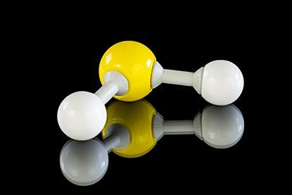 A plastic model of a molecule of hydrogen sulfide, with a yellow sulfur atom and two white hydrogen atoms