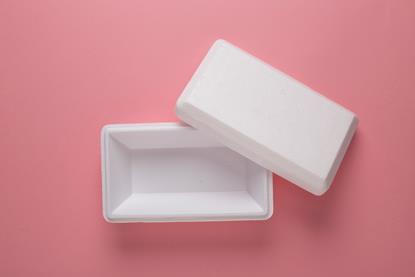 A white polystyrene food container with the lid off, on a red-pink background