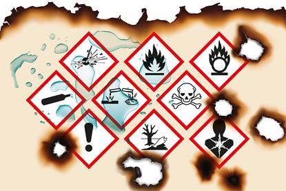 A piece of paper with warning symbols on that has been burned and splashed