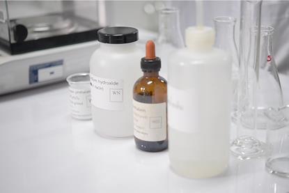A variety of glassware and containers of sodium hydroxide and phenolphthalein indicator in a laboratory