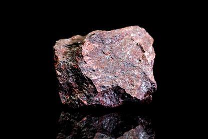 A photograph of a piece of red hematite iron ore against a black background