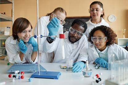 Students in a lab watching a teacher demonstrating a practical