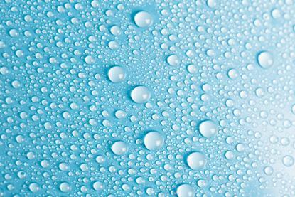 A close-up photograph of droplets of water on a bright blue surface
