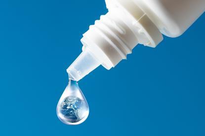A dropper bottle with a drop of liquid that contains a globe