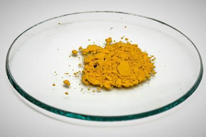 A sample of solid yellow lead iodide on a glass dish against a white background