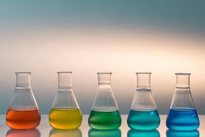 Five conical flasks with different coloured liquids arranged as a spectrum from red to green to blue