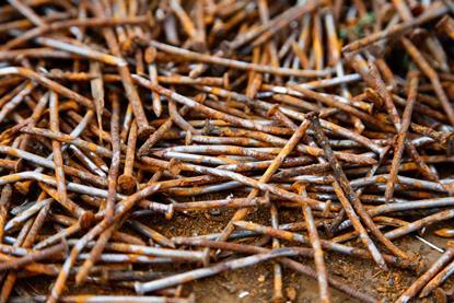A close-up photograph of a heap of long rusty nails