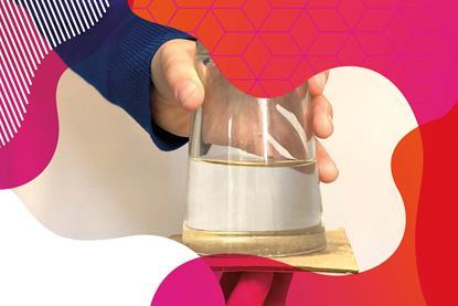 Photo of a glass with water in it, turned upside down with a piece of cardboard covering the bottom.