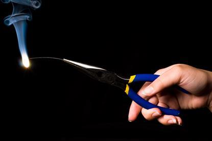 A photograph of a person's hand holding some burning magnesium wire in a pair of pliers