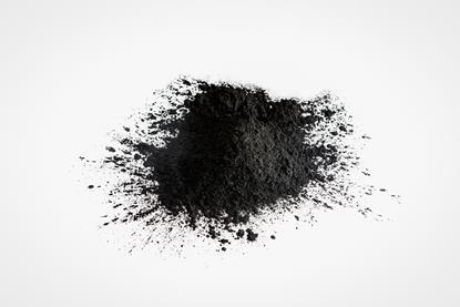 A small heap of black activated charcoal against a plain white-grey background
