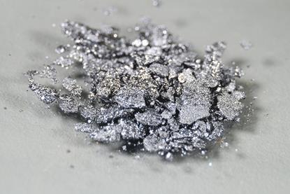A close-up photograph of silver-grey iodine crystals on a neutral background