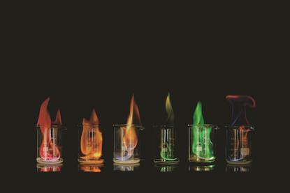 Six beakers with different coloured flames in a row