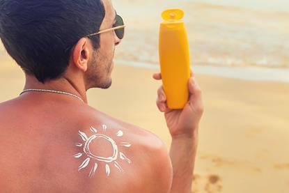 Man on a beach with sunscreen on his back