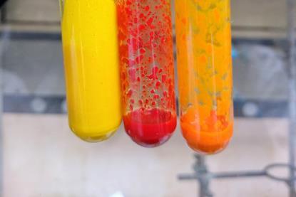 Test tubes containing yellow, red and orange substances formed by the combination of two solutions