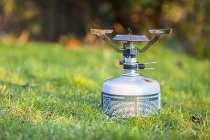 A small butane camping stove on grass