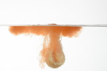 Picture of an orange bath bomb fizzing under water