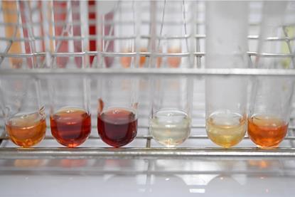 Six test tubes in a metal test tube holder, each containing a red-brown solution at different concentrations