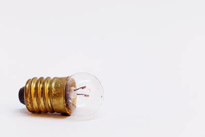 A close-up photograph of an old, small unlit light bulb, similar to those used in school experiments