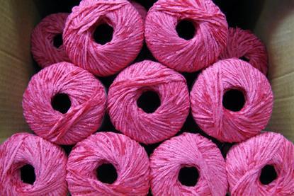 Rolls of pink-purple rayon stacked inside a cardboard box